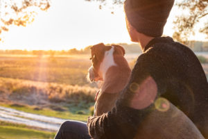 A teen sits with their dog while gazing out at the setting sun. This could represent a brighter future cultivated through trauma therapy in Delray Beach, FL. Learn more about the support a grief counselor in Palm Beach County, FL can offer by searching “trauma therapy Delray Beach” today.