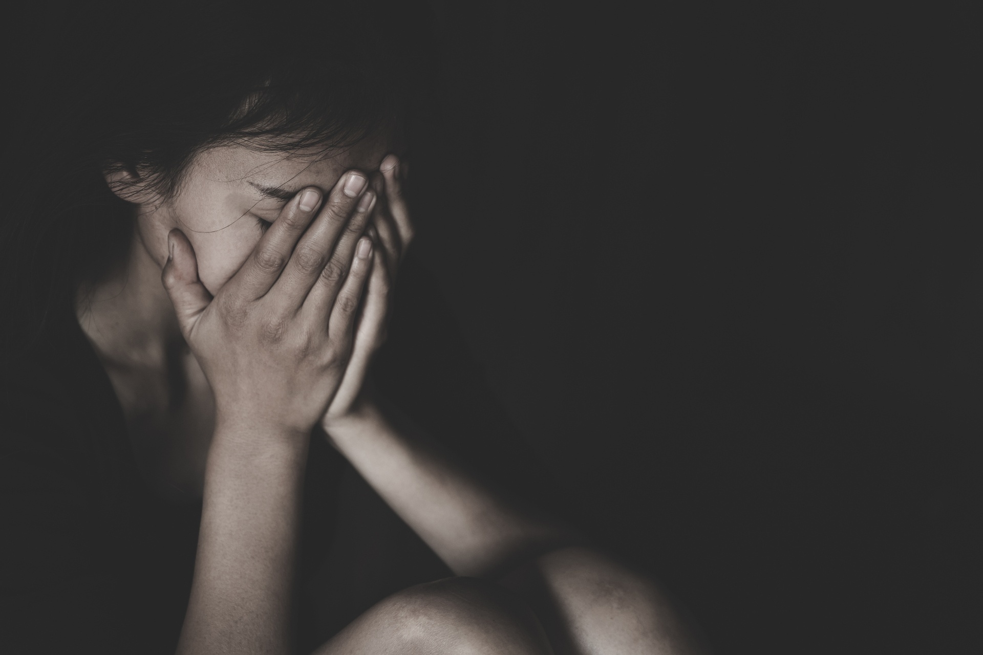 A close up of a woman covering her face against a dark background. A grief counselor in Palm Beach County, FL can offer support in overcoming grief symptoms in Palm Beach County, FL. We offer grief counseling in Delray Beach, FL and more.