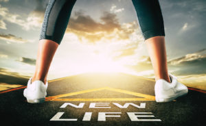 A person stands above a sign that reads "new life", representing the new start trauma treatment in Delray Beach, FL can help offer. Learn more about our services by contacting a trauma therapist in Palm Beach County, FL today.