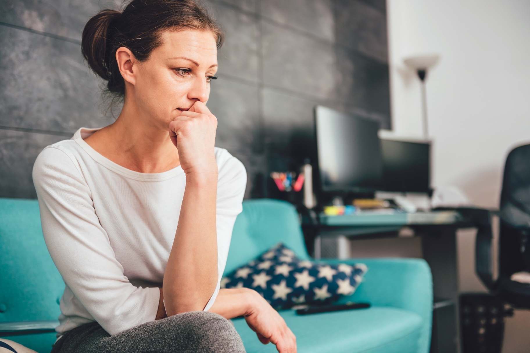 A woman sits with a concerned expression as she stares off into the distance. Learn how an anxiety therapist in Palm Beach County, FL can offer support with online anxiety treatment in Delray Beach, FL from the comfort of home. Or, search "anxiety therapy near me" today to learn more!