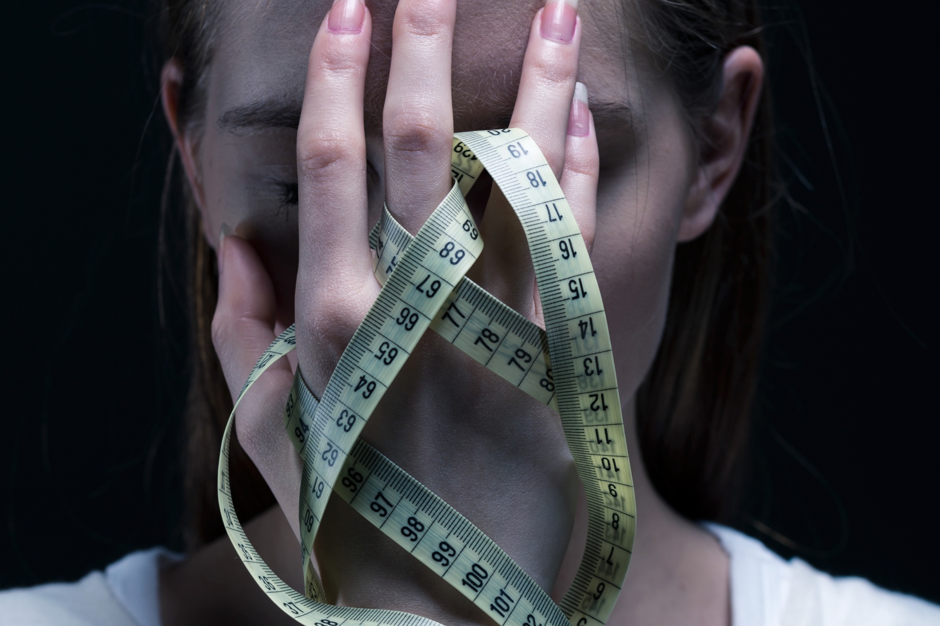 A touches her face while holding a measuring tape. Body image counseling in Palm Beach County, FL can help you overcome body image issues. Learn more about body dysmorphia treatment in Delray Beach, FL and other services by contacting a body image counselor in Delray Beach, FL.