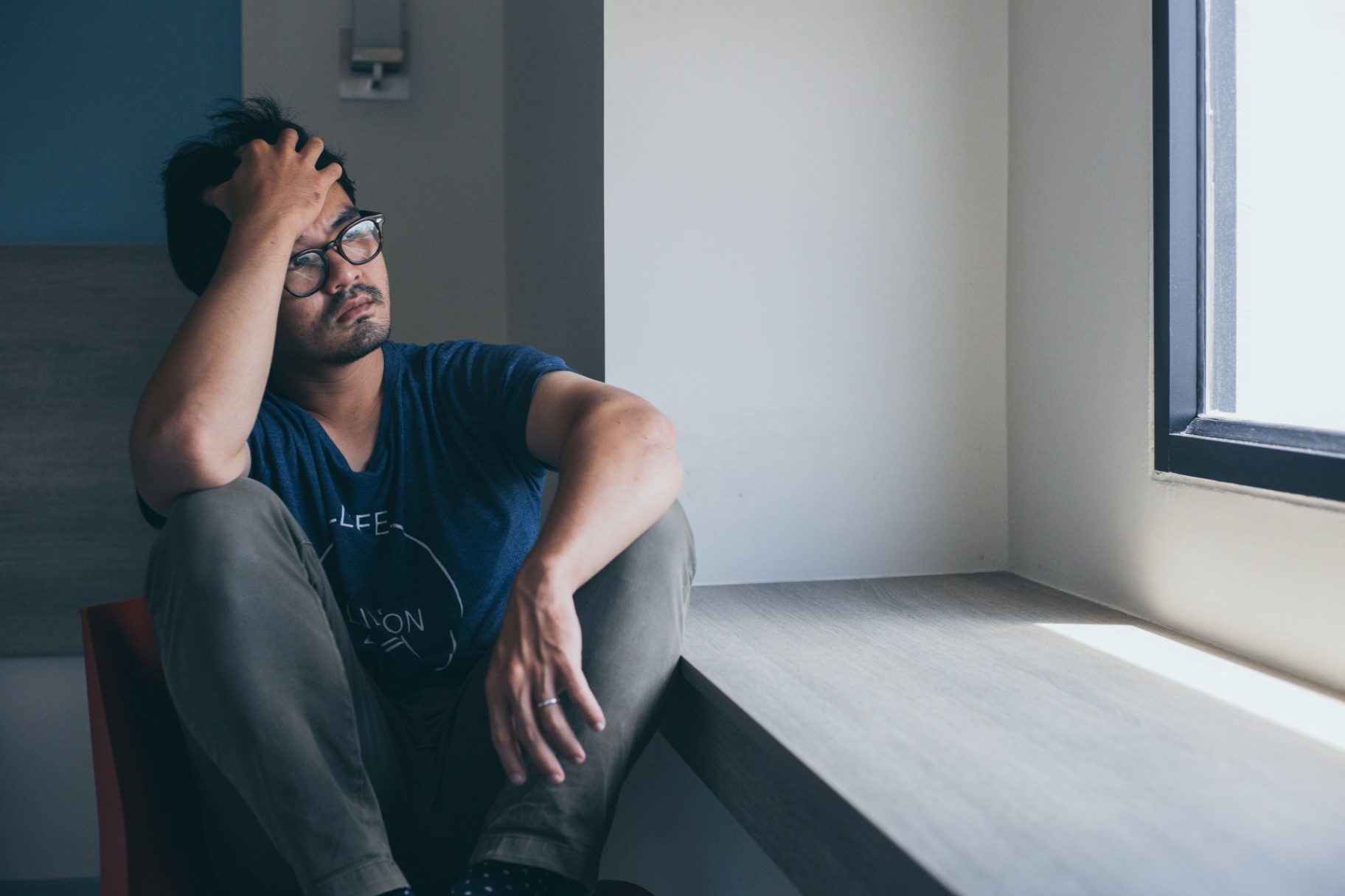 A man sits with his hand in his hair while looking out a window. Learn more about the support anxiety treatment in Palm Beach County, FL can offer by searching "anxiety therapy near me" or contacting an anxiety therapist in Palm Beach County, FL for more info!