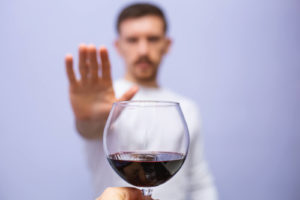 A close up of a person holding their hand up to a wine glass. This could represent the support an addiction therapist in Palm Beach, FL can offer. Learn more about addiction counseling in Palm Beach, FL by contacting an EMDR therapist to learn more.