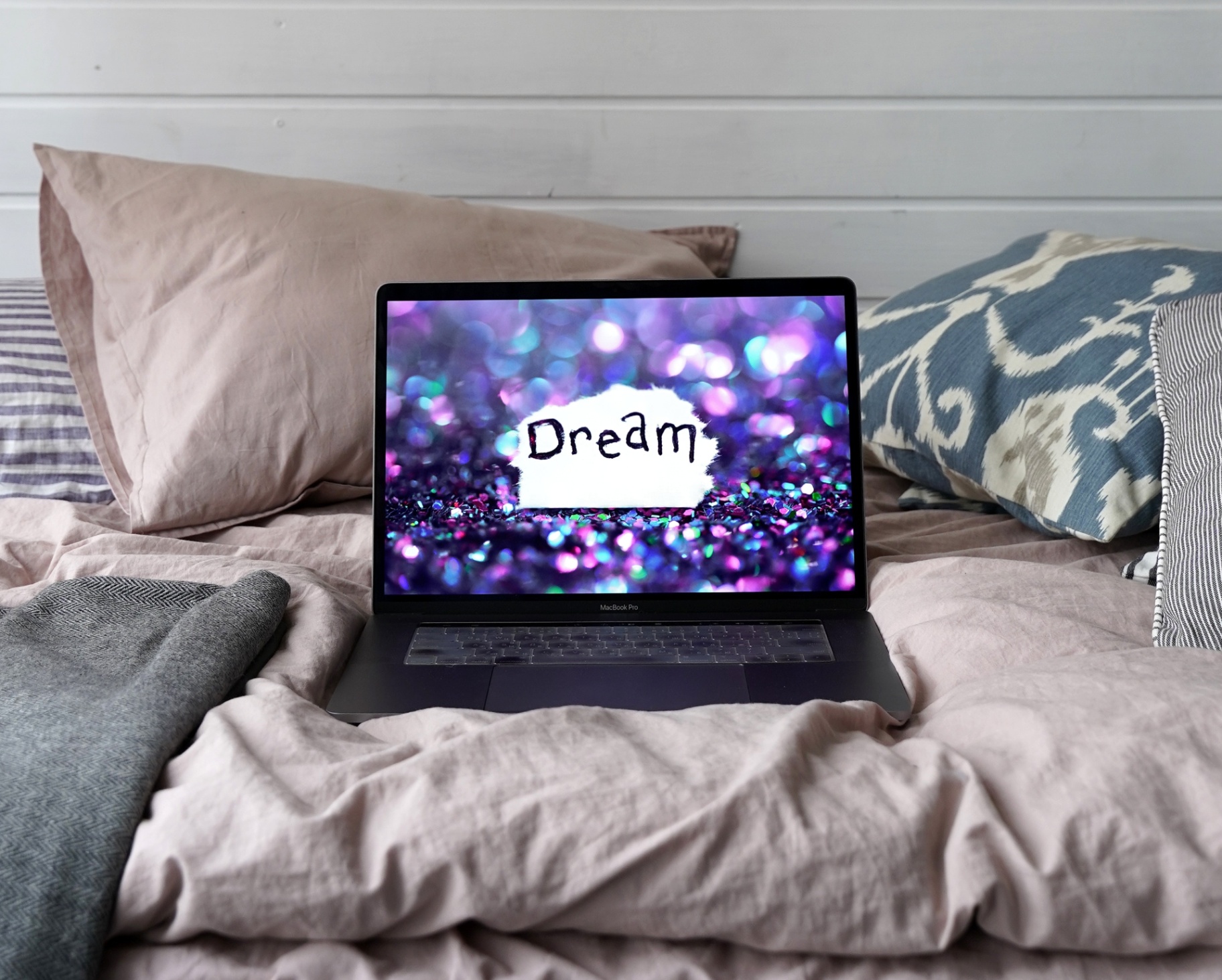 A laptop rests on a bed with the word dream on the screen. Learn how online therapy in Florida can offer support by searching for EMDR therapy in Palm Beach, FL