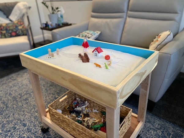 A sand tray with toys sits in the middle of a therapist’s room. This could represent the benefits of sand tray therapy in Delray Beach, FL. Learn more by searching for a child therapist near me today.