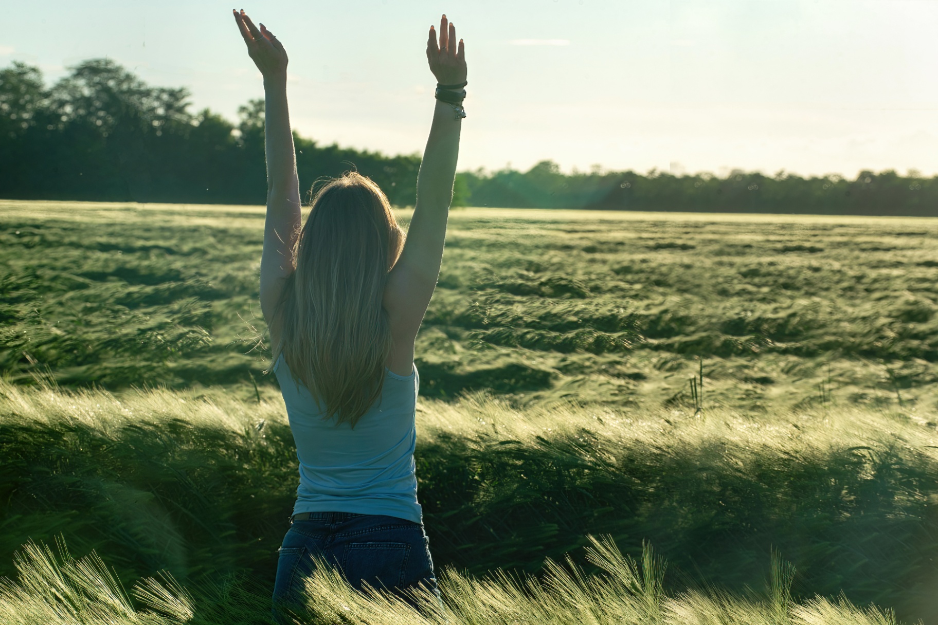 A woman raises her hands while standing in a field. Learn how a trauma therapist in Delray Beach, FL can offer support with overcoming symptoms and addressing social media use. Search for trauma treatment in Palm Beach County, FL or trauma therapy delray beach today. 