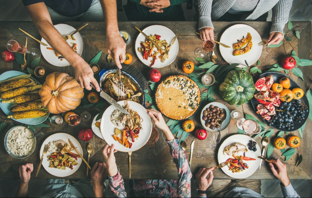 A top down view of people dishing up a buffet of food around a dinner table. This could represent the benefits of a family dinner. Learn how eating disorder treatment in Delray Beach, FL can offer support by contacting a binge eating therapist in Delray Beach, FL today.