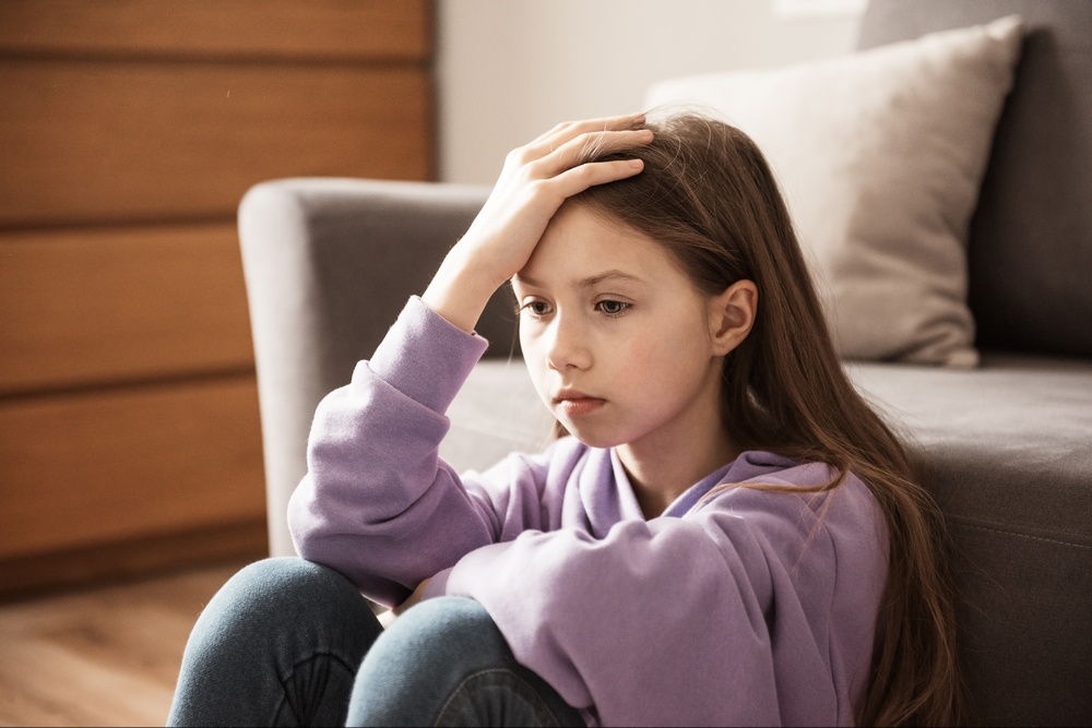 A young girl sits on the ground in front of a couch with a stressed expression. Learn how a therapist in palm beach county, fl can offer support with self care in adults and kids. Search for palm beach county, fl therapy or online therapy in Florida for more info.