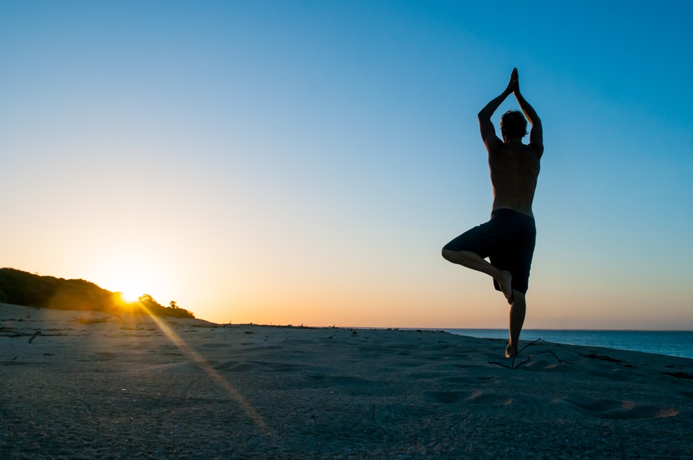 A person balances on one foot in a yoga pose as the sun rises over the beach. Learn how mindfulness techniques can help overcome the stress of past trauma. Contact an EMDR therapist in Palm Beach County, FL can help address. Learn more about EMDR in Palm Beach County, FL by contacting a binge eating therapist in Delray Beach, FL today. 