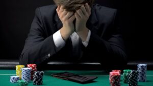 A man covers their face while sitting in front of a poker table. This could represent the struggles of process addictions like gambling. Contact an addiction therapist in Palm Beach County, FL to learn more about different types of addiction in Palm Beach, FL. Search for addiction counseling in Delray Beach, FL today. 