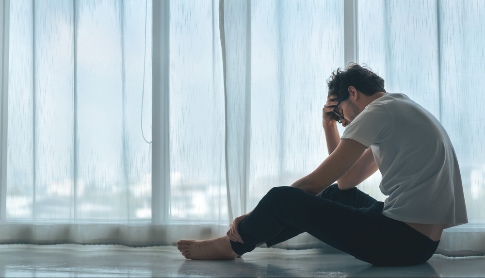 A man sits alone next to a window while hiding his expression. Learn how EMDR in Palm Beach County, FL can help address depression. Search for EMDR therapy in Delray Beach, FL or