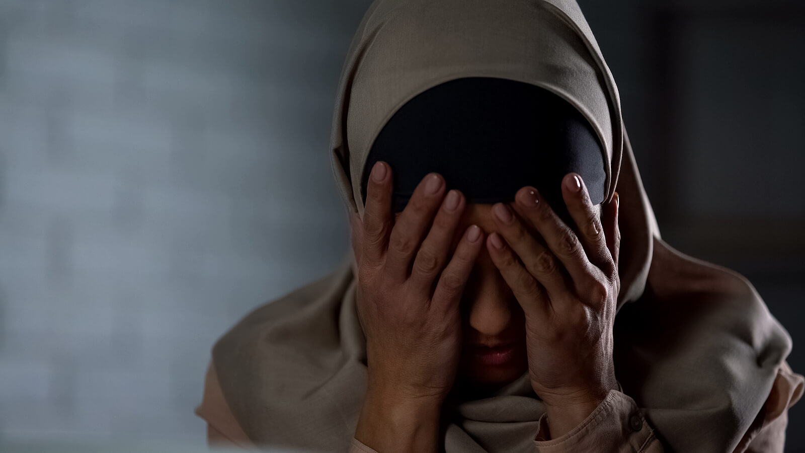 A woman covers her face while hiding an anxious expression. Learn more about how an anxiety therapist in Palm Beach County, FL can help with overcoming body anxiety in Palm Beach, FL. Search for anxiety therapy near me today.